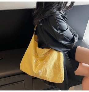 Close-up of a large yellow canvas tote bag with 'Grow your fun' print on a black jacket