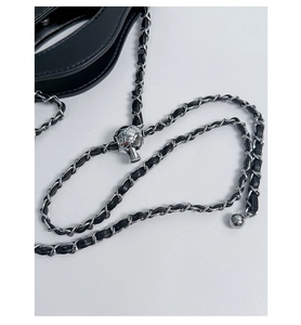 Detailed macro view of silver metal ball buckle with woven chain strap for chic handbag