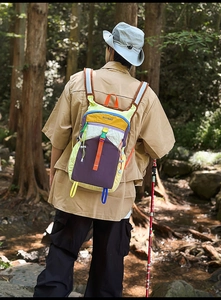 Detail view of colorful nylon hiking backpack in a scenic forest and stream outdoor setting