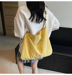 Close-up of yellow canvas tote bag with bow print and adjustable black shoulder strap
