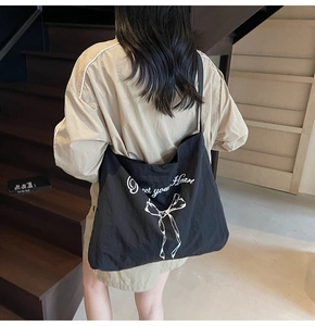 Detailed back view of a large black canvas tote bag with a white bow and heart text