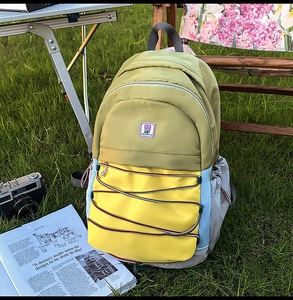 Détail d'un sac à dos en nylon multicolore avec écusson floral posé sur l'herbe