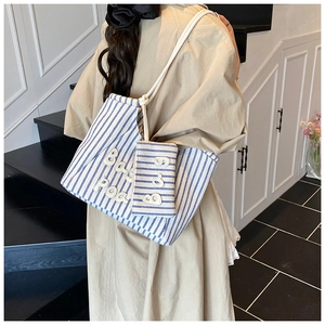 Detail of blue striped canvas tote bag with small matching pouch and letter patch embroidery