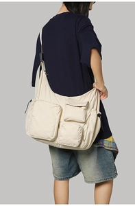 Model wearing a large capacity beige messenger bag with functional utility pockets