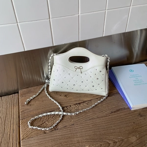 Nahaufnahme der cremefarbenen Stepptasche mit silberner Schleife und Diamantakzenten