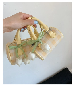 Détail du sac cylindrique à carreaux jaunes avec pendentif tulipe et nœud en soie vert