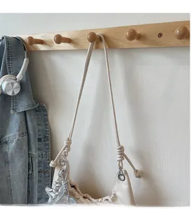 Detail of beige pleated tote bag featuring knotted rope handles and silver star charm
