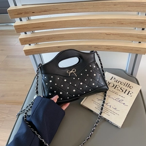 Detailansicht der gesteppten schwarzen Ledertasche mit Metallschleife und Strass