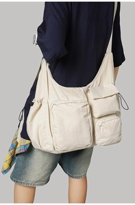 Detailed back view of a beige multi-pocket messenger bag on a model for casual wear