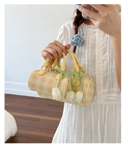 Detail of yellow checkered cylinder bag with delicate white tulip ribbon charms