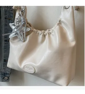 Detail view of cream Hobo shoulder bag with silver star and balloon dog charms