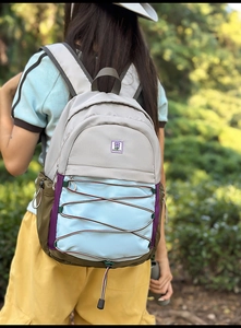 Détail d'un sac à dos multicolore avec cordon élastique porté en pleine forêt