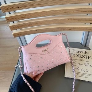Detail einer rosa gesteppten Handtasche mit glitzernden Strasssteinen und goldener Schleife