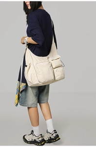 Detail view of cream multi-pocket messenger bag featuring large capacity and nylon texture