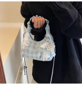 Detail of light blue checkered crossbody bag with pearl heart charm and lace bow decor