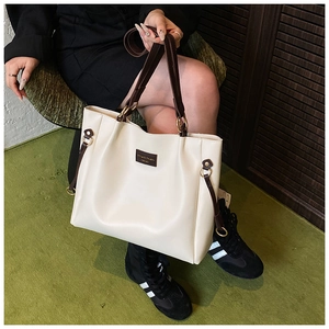 Dettaglio di una grande borsa tote crema con manici marroni e coulisse laterali