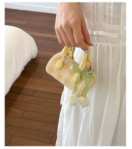 Detail of yellow checkered mini cylinder bag with green ribbon and tulip pendant charm