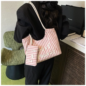Detail of red striped canvas tote bag with embroidered letters and matching small pouch