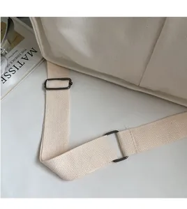 Detail of adjustable canvas strap with gunmetal buckle on minimalist beige tote bag