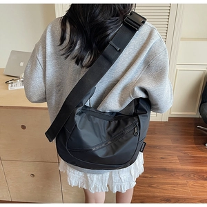 Detail of black nylon crescent shoulder bag with wide strap and round zipper pull