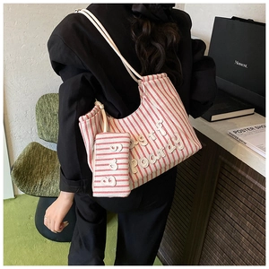 Detail of red and white striped canvas tote bag with 3D letters and matching mini pouch