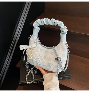 Detail of blue plaid hobo bag with lace bow, pearl heart charm and silver chain strap