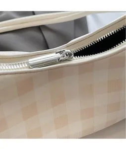 Detailed macro view of the silver polished metal zipper pull on the checkered handbag