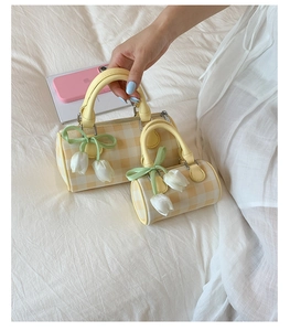 Détail de sacs cylindriques à carreaux jaunes avec pendentif tulipe et rubans verts