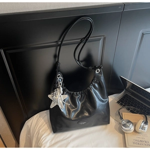 Détail d'un sac hobo en cuir noir brillant avec un charme d'étoile de mer argenté