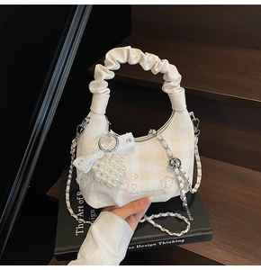 Detail of checkered cream bag with pleated cloud handle and pearl heart charm decor