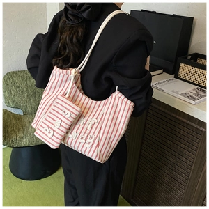 Detail of red and white striped canvas tote bag set with mini pouch shown on a shoulder