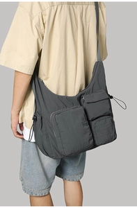 Detail of dark grey utility messenger bag with multi-pocket texture and nylon fabric