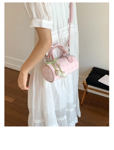 Detail of pink plaid cylinder bag with tulip charm and bow on lace dress background