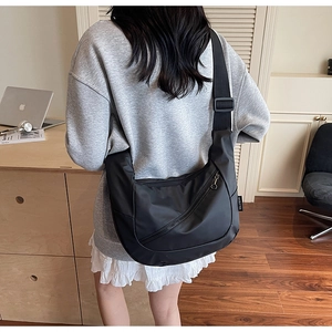 Close-up of black crossbody messenger bag with adjustable strap and zip detail