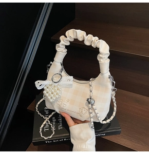 Detail of hobo bag featuring heart embroidery, pearl charm, and lace bow decoration