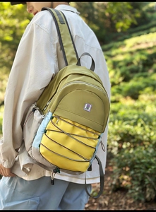 Détail du sac à dos color-block avec cordons élastiques et logo en décor forestier