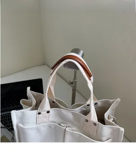 Detail of canvas tote bag with brown leather handles and reinforced metal rivets