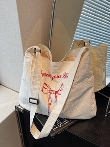 Minimalist canvas tote bag with red bow print and adjustable black shoulder strap