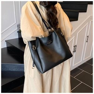 Dettaglio della grande borsa tote in pelle nera con eleganti anelli dorati su una modella