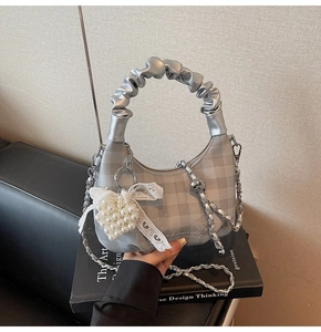 Detail of silver checkered hobo bag with lace bow, pearl heart and metal chain strap