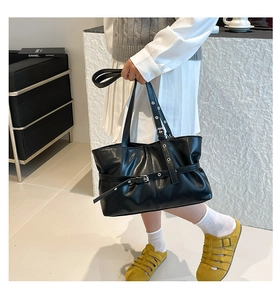 Détail d'un grand sac cabas noir en cuir PU avec des lanières décoratives à œillets argentés