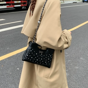 Detail einer schwarzen Stepptasche mit Strass und goldener Schleife an einem Modell