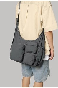 Detail of multi-pocket dark gray nylon crossbody bag with durable zippers and wide strap