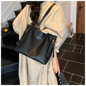 Grande borsa tote nera minimalista indossata da una modella in un ambiente moderno