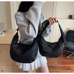 Detail of black crescent crossbody bag with adjustable wide strap and front zipper pocket