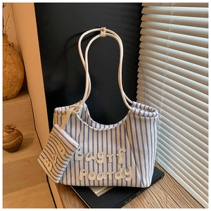 Detailed close-up of blue striped canvas tote bag with embroidered logo and small pouch