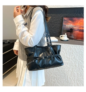 Détail du sac cabas en similicuir noir avec œillets métalliques et boucles décoratives
