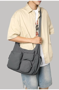 Detail of dark grey nylon messenger bag showing three functional utility front pockets