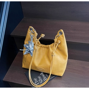 Gros plan du sac hobo en cuir jaune vif avec breloque étoile sur un escalier
