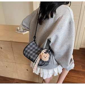 Detail of hobo shoulder bag with grey plaid pattern, plush bear charm and striped scarf